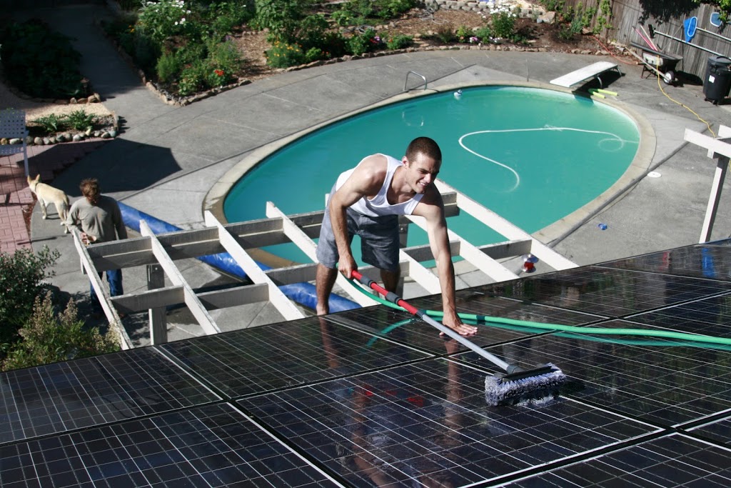 Spring cleaning enthusiast washing solar panels near a pool