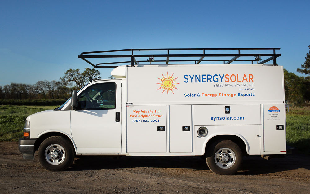 Synergy Solar and Energy Storage Systems service van on a grassy field