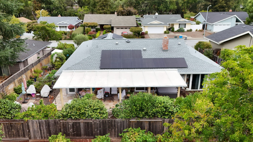 A home among others in a residential neighborhood with solar panels on the roof.